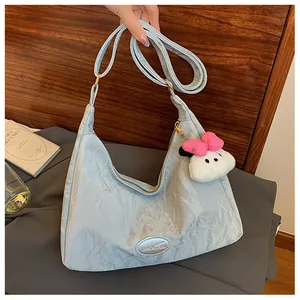 Detail of light blue textured hobo bag with adjustable strap and cute plush charm