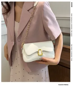 White faux leather shoulder bag with gold chain and horseshoe buckle shown on a model