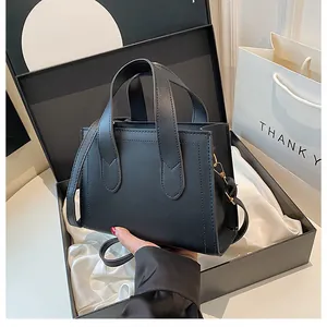 Detail of black matte leather tote bag with gold metal buckles and crossbody strap