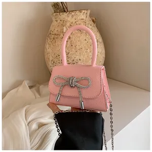 Detailopname van roze leren handtas met grote strass-strik en zilveren kettingriem
