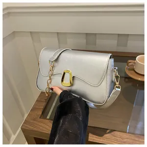 Detail of silver-grey leather shoulder bag featuring a gold trapezoid metal buckle