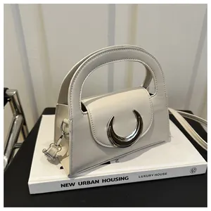 Close-up of semi-circular leather handbag with silver crescent buckle and thin shoulder strap