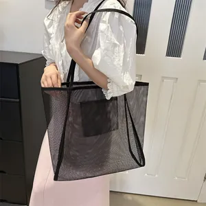 Bolso tote minimalista de malla negra con bolsillo interior mostrado por una modelo real
