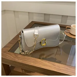 Detail of silver chain bag with gold U-shaped buckle on a wooden coffee table