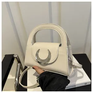 Detailed close-up of cream leather handbag featuring a silver crescent moon metal logo
