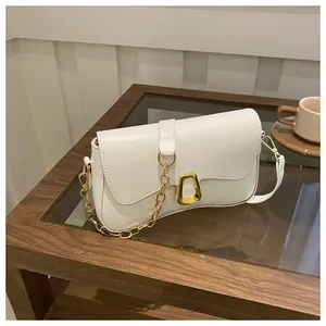 Close-up of beige leather shoulder bag with a gold metal chain and unique buckle detail