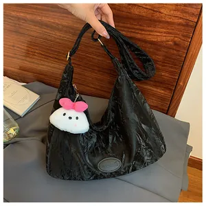 Detail of black pleated crossbody bag featuring a cute white bunny charm with pink bow