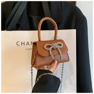 Detail van bruine leren handtas met een grote, sprankelende strik van strass-steentjes
