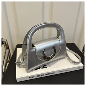 Detail of silver metallic mirror finish handbag with crescent metal buckle and handle