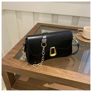 Detailed shot of black patent leather baguette bag with a stylish gold buckle and chain