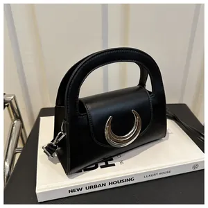 Detailed view of black matte leather handbag with iconic silver crescent metal buckle