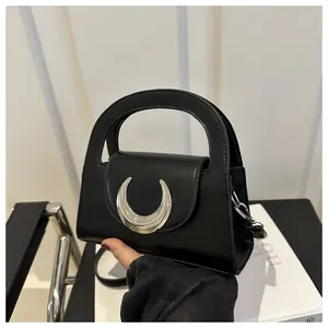 Close-up of black leather handbag featuring a signature silver crescent moon metal buckle