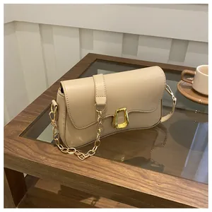 Detail of minimalist beige leather shoulder bag with gold chain and geometric buckle