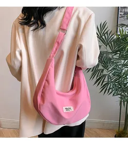 Detail of pink waterproof nylon hobo bag with adjustable strap on white blazer