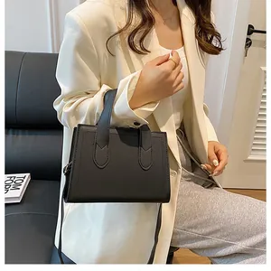 Minimalist black leather tote bag with elegant curved stitching detail and shoulder strap