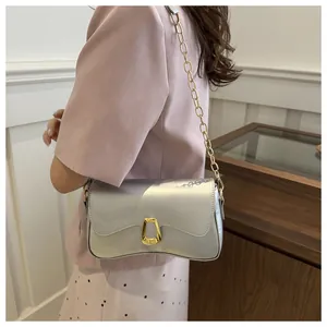 Detail of light blue glossy chain bag with golden trapezoidal buckle on female model