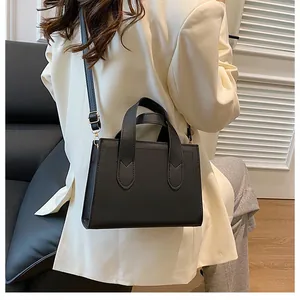 Classic black structured handbag worn as a crossbody bag shown on a female model