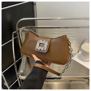 Detail of retro brown leather baguette bag with large square crystal buckle and chain strap