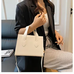 Model wearing ivory leather crossbody handbag with dual handles and slim shoulder strap