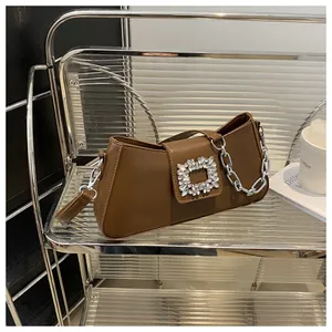 Detail of caramel leather underarm bag featuring a crystal-encrusted square buckle and chain