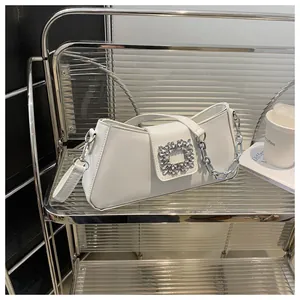 Detail of white leather handbag with silver rhinestone buckle and metal chain strap