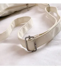 Detail of adjustable gunmetal buckle on minimalist ivory canvas shoulder strap