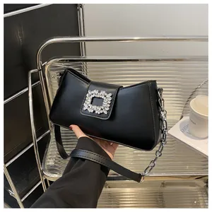Detail of black underarm bag featuring a crystal-embellished buckle and silver chain