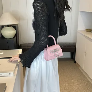 Chique roze mini-handtas met strik en zilveren ketting in een stijlvolle kamer