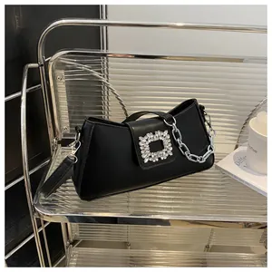 Detail of black leather handbag featuring a sparkling silver rhinestone square buckle