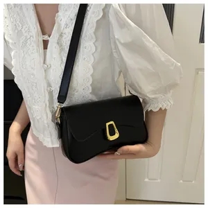 Detailed view of black leather shoulder bag with a gold metal clasp shown on a model