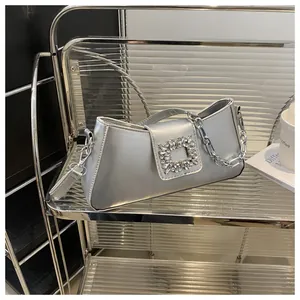 Detail view of silver baguette bag featuring a crystal buckle and chunky metal chain strap