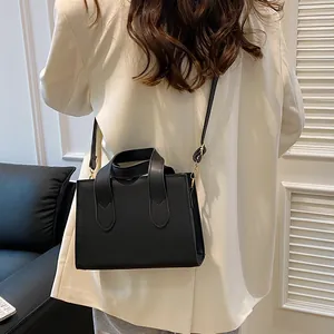Classic black leather tote bag with gold hardware worn over a white blazer for work