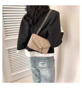 Détail d'un sac à main beige effet crocodile avec pampille en S et bandoulière chaîne