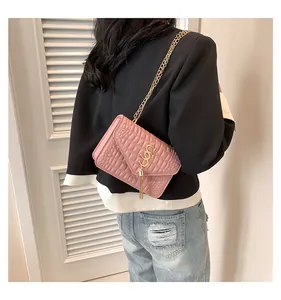Détail du sac bandoulière rose à motif crocodile avec chaîne et pompon doré