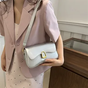 Silver metallic shoulder bag with gold U-shaped buckle on female model in pink suit