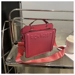 Detail view of pink leather tote bag with RICH RABBIT embossed text and wide strap