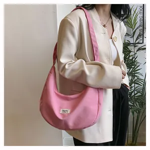 Close-up of pink crescent canvas bag worn by a model in a minimalist beige blazer