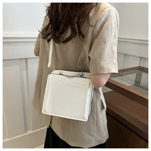 Detail view of a white leather crossbody bag featuring the embossed Rich Rabbit logo design