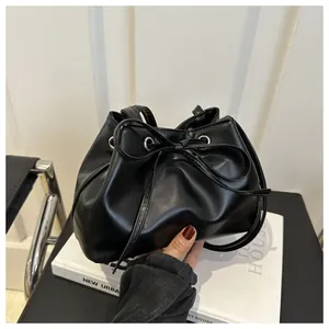 Detail of black leather drawstring bucket bag with elegant bow and silver eyelets