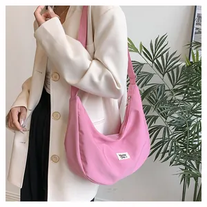 Detail of pink half-moon nylon crossbody bag featuring a woven brand logo label
