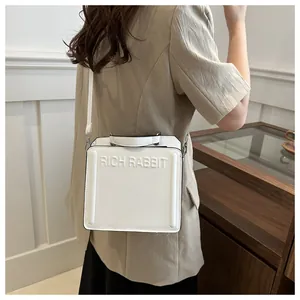Detailed side view of white leather tote bag with RICH RABBIT embossed lettering