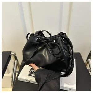 Detail shot of black leather bucket bag featuring drawstring closure and silver eyelets