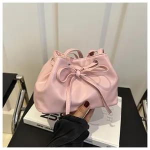 Detailed shot of pink PU leather bucket bag with drawstring closure and bow decoration