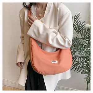 Detailed view of coral crescent canvas bag with brand label on casual outfit