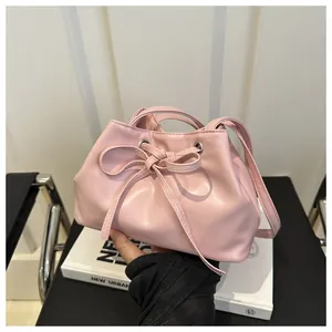Detailed close-up of pink drawstring bucket bag with bow tie knot and smooth PU leather