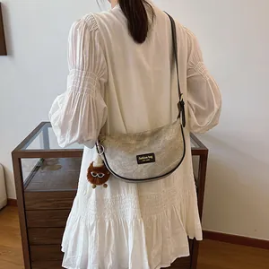 Grey crescent shoulder bag with monster pendant shown on model in white dress