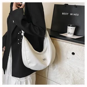 Close-up of a white crescent crossbody bag with adjustable strap and brand tag detail