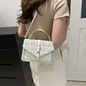 Elegant white tweed shoulder bag with gold horseshoe buckle worn by a female model