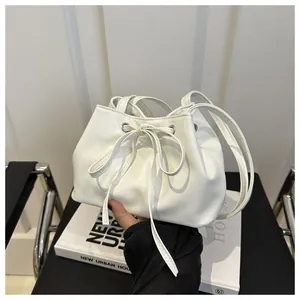 Detailed view of white drawstring bucket bag with metal eyelets and bow accents