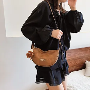 Brown half-moon crossbody bag in matte faux leather with a cute plush doll charm